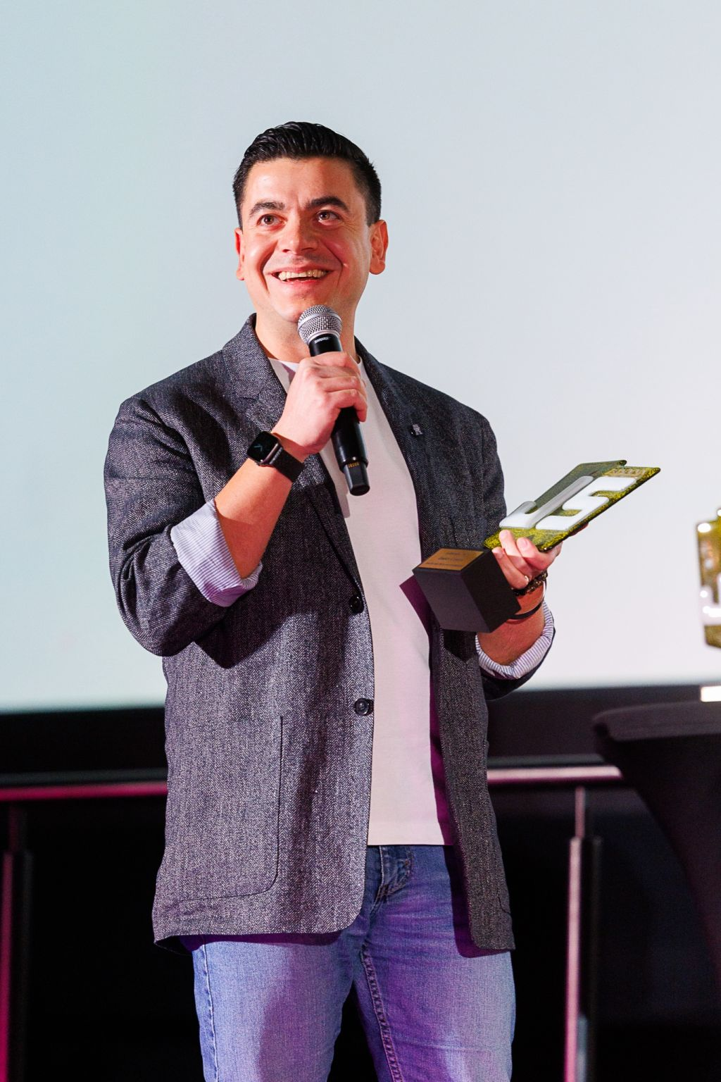 Önder Ceylan speaking on stage while holding an award